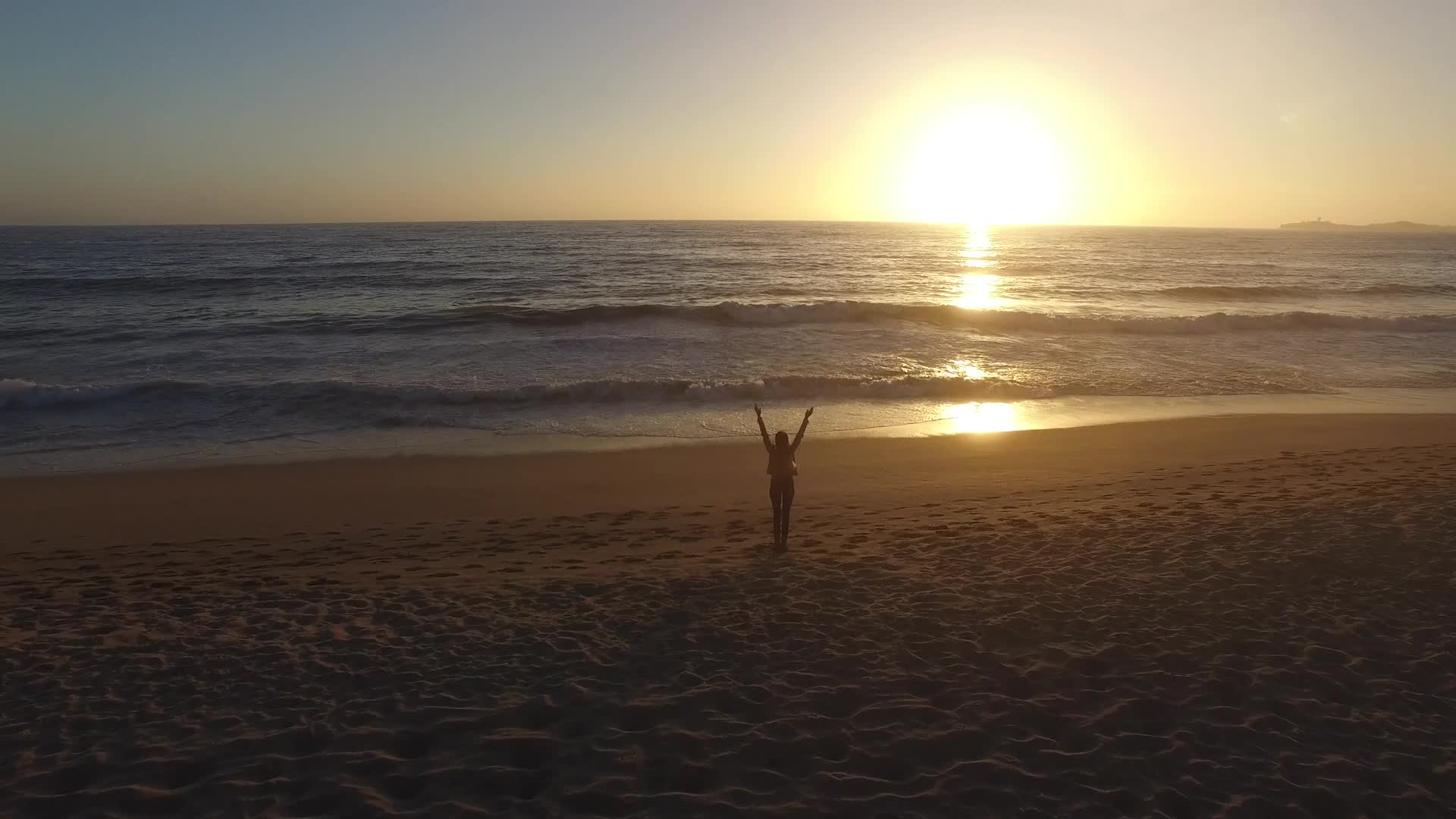 夕阳海边的女孩迎风挥手